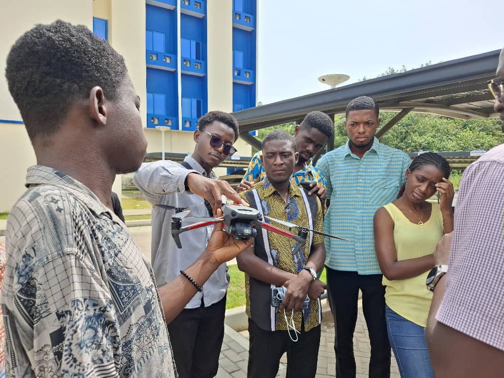 A student, having a feel of the drone, while an assistant instructor shows him where the switch is.