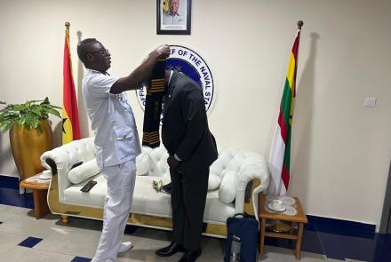 Chief of the Naval Staff, Ben Baba Abdul putting a sash on Prof. Mattah